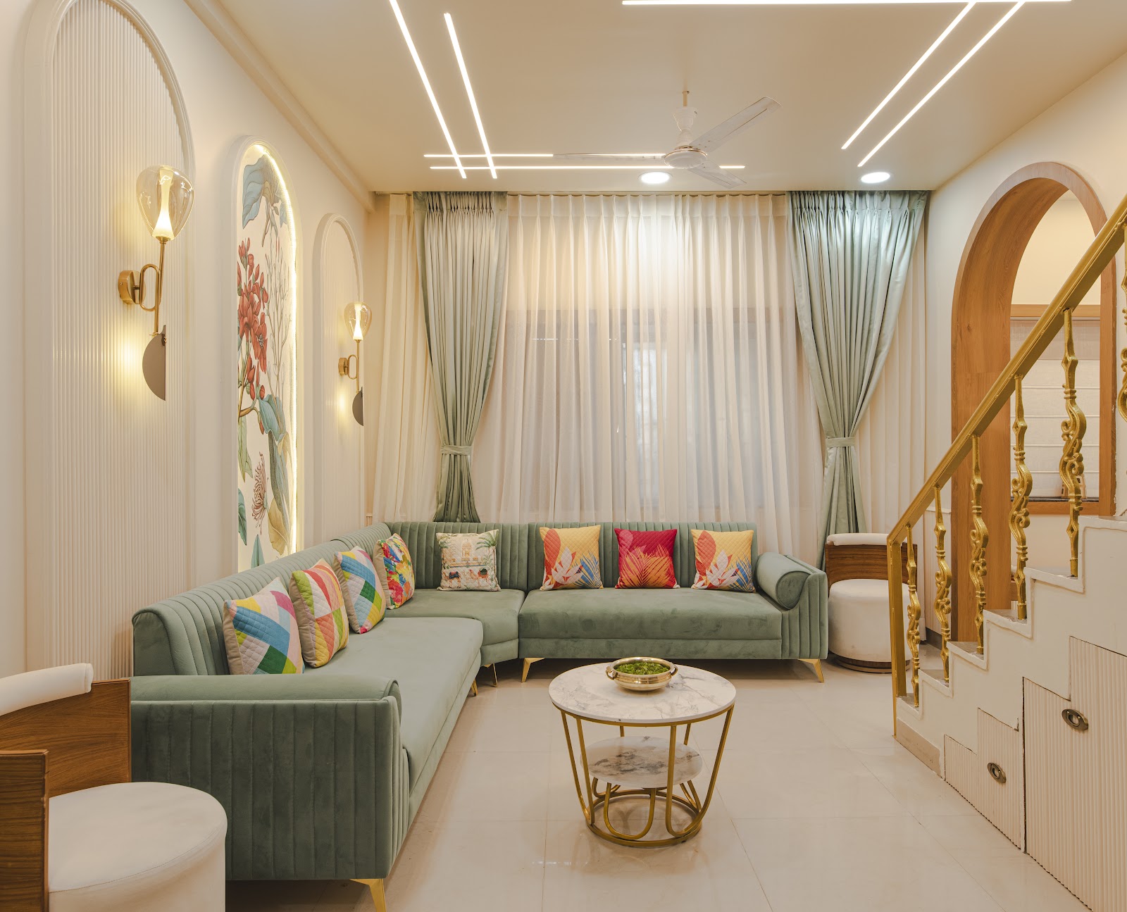 A living room designed by Style-Home, with a channel-tufted sage velvet sectional beneath arched wall niches